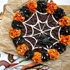 a cake decorated with orange and black icing on top of brown paper wrappers