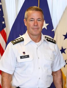 a man in uniform standing in front of flags