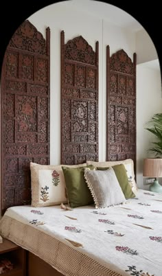 a bed with pillows and decorative wooden headboard