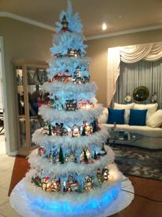 a white christmas tree with blue lights in the center and decorations around it on top