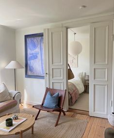 a living room filled with furniture and a painting hanging on the wall above it's doorway