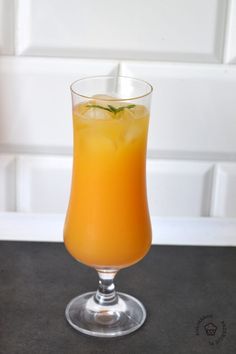 a glass filled with orange juice and garnished with a green sprig