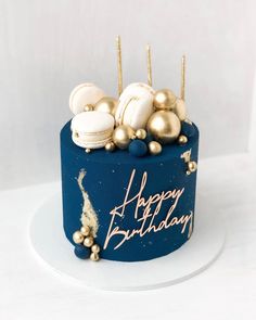 a birthday cake with gold and white decorations on it's blue frosted surface