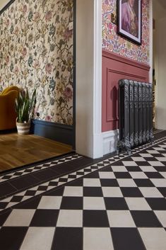 a room with a black and white checkered floor, pink wallpaper and an ornate radiator