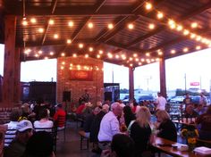 a group of people sitting at tables in a restaurant with lights hanging from the ceiling