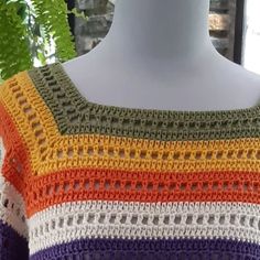 a crocheted sweater is displayed on a mannequin