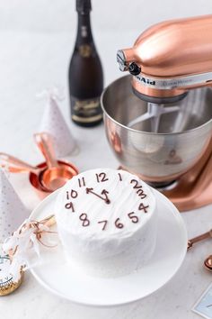 a white cake sitting on top of a plate next to a mixer and other items