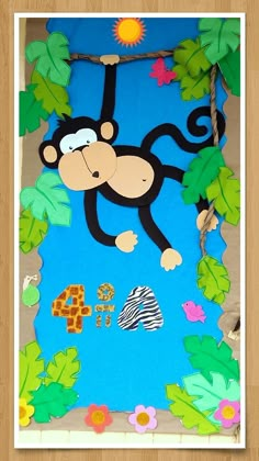 a paper cut out of a monkey hanging from a tree with leaves and flowers on it