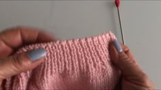 someone is knitting something with a needle on the end of a piece of pink yarn