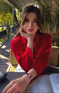 a woman is sitting at a table with her hand on her chin and looking off to the side