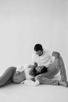 a man and woman laying on the ground with their arms around each other as they cuddle