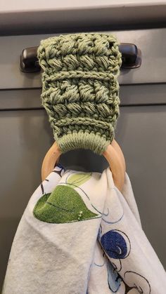 a green crocheted dishcloth hanging from a hook on a cabinet door handle