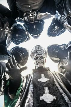 a group of people standing around each other with their hands in the air and wearing helmets