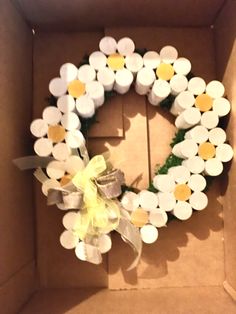 a cardboard box with a wreath made out of white and yellow cupcakes