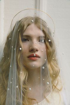 a woman wearing a veil with pearls on it