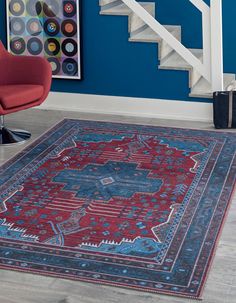 a blue and red area rug in front of a stair case with a painting on the wall