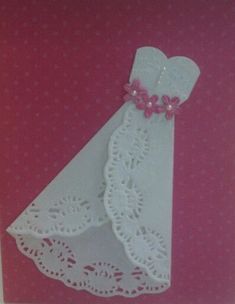 a card with a white dress and pink ribbon on the front, against a pink background