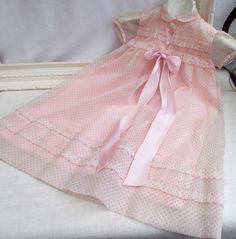 This little gown is absolutely gorgeous. Hand made in France in the 50's. Tiny pink spot on white organza over pink lining.  Such pretty detail.  The pleated organza banding has been edged by hand with the tiniest of stitches. The darling puff sleeves and little collar are just lovely and the satin bow is just the job to finish it off. Fastening is at the front with three press studs hidden underneath buttons. Condition is very good,  The organza rustles when handled as if it were made yesterday Pink Short Sleeve Gown For Spring, Fitted Pink Swiss Dot Dress, Pink Short Sleeve Summer Gown, Short Sleeve Pink Summer Gown, Polka Dot Ruffled Wedding Dress, Sweet Pink Dress For Baptism, Sweet Pink Baptism Dress, Pink Vintage Short Sleeve Dress With Lace Trim, Pink Vintage Dress With Lace Trim And Short Sleeves