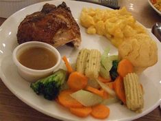 a white plate topped with meat, veggies and macaroni and cheese