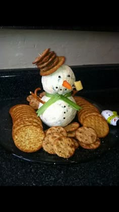 a black plate topped with crackers and a snowman