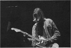 black and white photograph of a man playing an electric guitar in front of a microphone