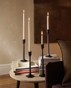 three candles sitting on top of a table next to some books and a purple chair