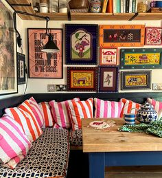 a room filled with lots of colorful pillows and pictures on the wall above it's couches