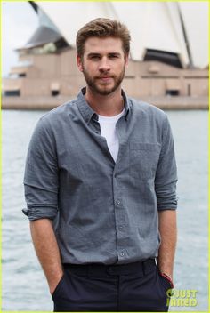 a man standing in front of the sydney opera house with his hands in his pockets