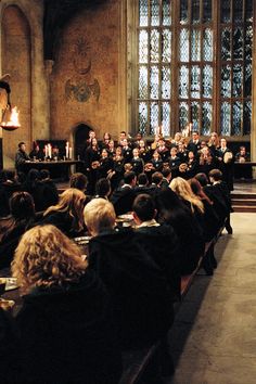 a large group of people sitting in front of a stage with candles on the table