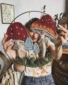 a woman holding two knitted hats in front of her face