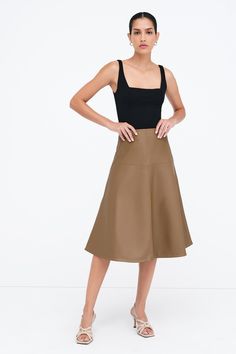 Our Lexi Skirt brings new life to the timeless A-line cut with architectural seam detailing that creates a striking silhouette. Fashioned from stretchy vegan leather with an invisible side zip, she offers an easy fit that accentuates your waist. Whether she's dressed up or down, Lexi arrives to every occasion with equal elegance. | Astrid, in latte and in black, is 5'9" (175 cm) tall, wearing size XS. Shannon, in black, is 5'8 (173 cm) tall, wearing size M. Total length is approximately 29.5" (7 Modern A-line Lined Skirt, Modern Full Skirt Fitted, Modern Fitted Full Skirt, Modern A-line Relaxed Skirt, Modern A-line Skirt, Chic Brown A-line Bottoms, Modern A-line Skirt For Work, Chic Brown A-line Skirt, Vegan Leather Skirt