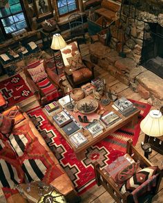 a living room filled with furniture and a fire place next to a stone fireplace in a log cabin