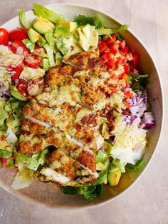 a bowl filled with salad and dressing on top of a table