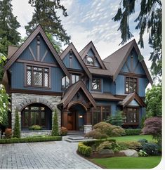 a large blue house with lots of windows and landscaping around the front door, on a nice day