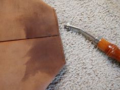 a brown leather tie laying on the floor next to a piece of cloth with a wooden handle