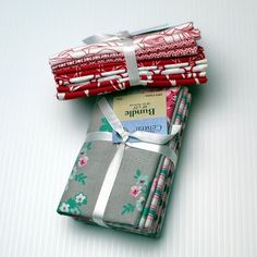 four folded fabric pieces sitting on top of each other in different colors and patterns, with ribbons tied to them