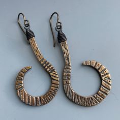 I made these bronze incised curls based on a favorite pair of vintage ethnic earrings.   Black wired caps and niobium wires  complete this tribal fusion design. Adjustable Spiral Brass Earrings, Hand Forged Bohemian Bronze Earrings, Hand Forged Bronze Bohemian Earrings, Bronze Brass Wire Wrapped Hoop Earrings, Bronze Wire Wrapped Hoop Earrings, Artisan Bronze Copper Earrings, Unique Adjustable Brass Wrap Earrings, Artistic Handmade Bronze Earrings, Antique Gold Copper Earrings With Antique Finish