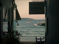 an open door leading to the beach with boats in the water and a sign that says thalasssa