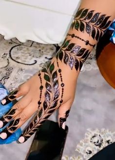 a woman's hand with hennap and tattoos on her left arm, next to a blue shoe