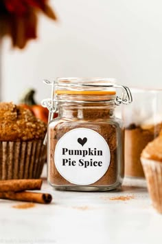 pumpkin pie spice in a glass jar next to muffins and cinnamon stickers