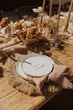 the table is set with plates, napkins and flowers on it's placemat