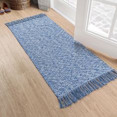 a blue rug with fringes on the floor in front of a window and shoes