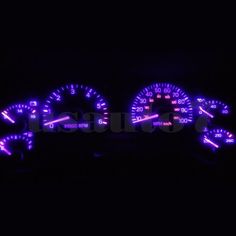 two speedometers in the dark with blue lights on them, all lit up