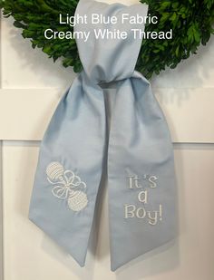 a light blue fabric scarf with it's a boy written on it