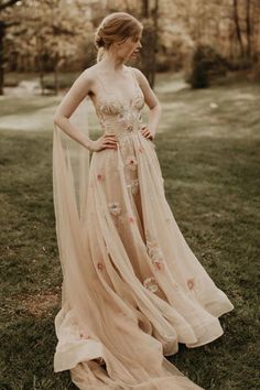 a woman standing in the grass wearing a dress