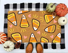 a pair of brown shoes sitting on top of a door mat next to pumpkins