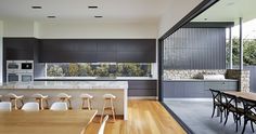 an open kitchen and dining area with wooden flooring, white counter tops and chairs