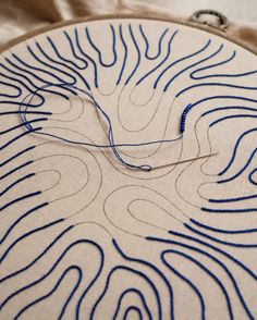 a close up of a piece of cloth with blue thread on it and a circular object in the background