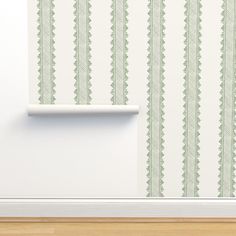 an empty room with a white wall and green striped wallpaper on the wall next to a shelf