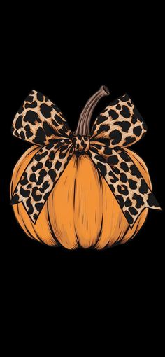 a leopard print pumpkin with a bow on it's head, sitting in front of a black background